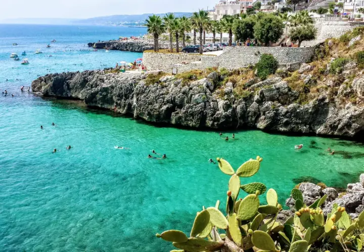 Plage rocheuse et eaux turquoise à Castro, Italie. Des baigneurs profitent du soleil et de la mer.