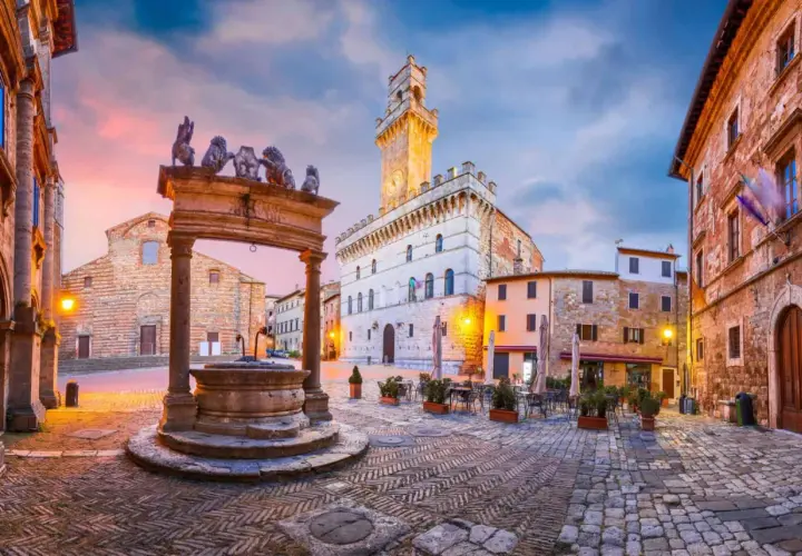 Place du peuple à Montepulciano, Toscane, avec sa fontaine ornée de lions et son hôtel de ville imposant.
