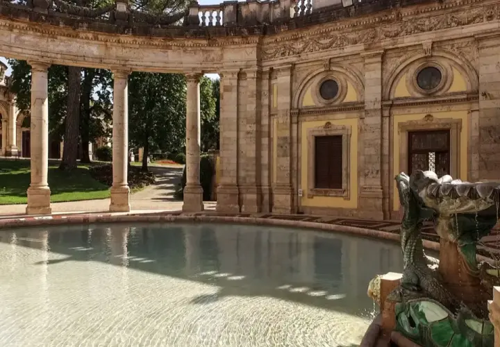 Fontaine sculptée d'un dragon à Montecatini, avec une arcade de colonnes en arrière-plan et un bassin d'eau claire.
