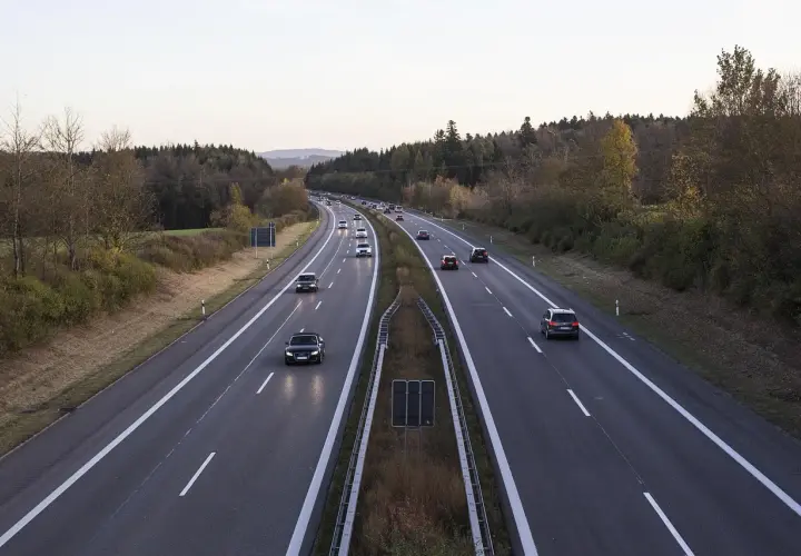 Voiture circulant en Italie sur une autoroute bordée d'arbres aux couleurs d'automne.