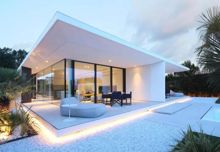 Villa moderne à Jesolo avec grandes baies vitrées, terrasse illuminée et mobilier extérieur invitant.