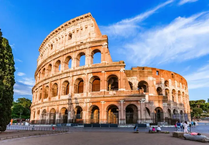 Le Colisée de Rome en novembre, sous un ciel bleu éclatant. Des visiteurs profitent de la douceur de l'automne.