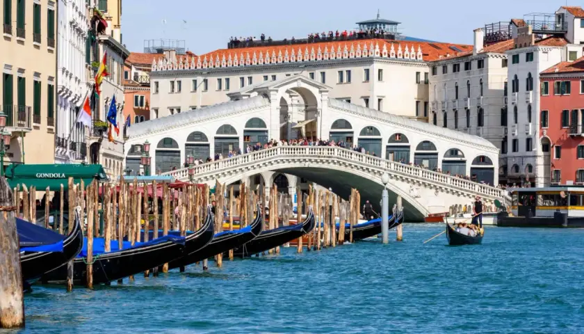 Gondoles amarrées près du célèbre Ponte di Rialto, avec des touristes admirant la vue sur le Grand Canal.