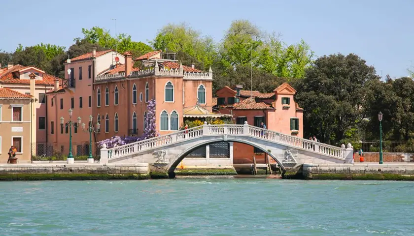 Pont vénitien fleuri, bordé de maisons aux toits de tuiles rouges. Un charmant jardin venise s'épanouit sur les berges.