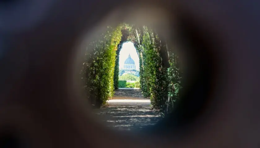 Un chemin bordé de verdure mène à la coupole de Saint-Pierre, une vision de Rome insolite et secrète à travers un trou de serrure.