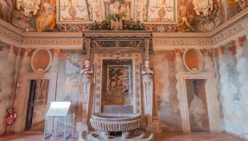 Intérieur de la Villa d'Este : une fontaine ornée de sculptures et de fresques murales dépeignant des scènes mythologiques et des paysages.