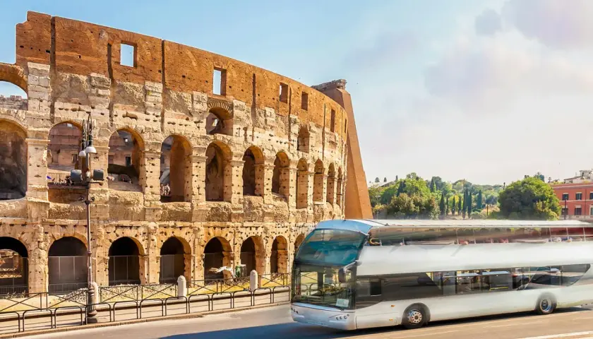 Un bus touristique passe devant le Colisée. Une carte du métro de Rome serait utile pour naviguer dans cette ville historique.