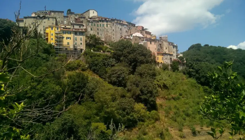 Village d'Ameglia perché sur une colline verdoyante, avec des maisons colorées et un ciel bleu éclatant.