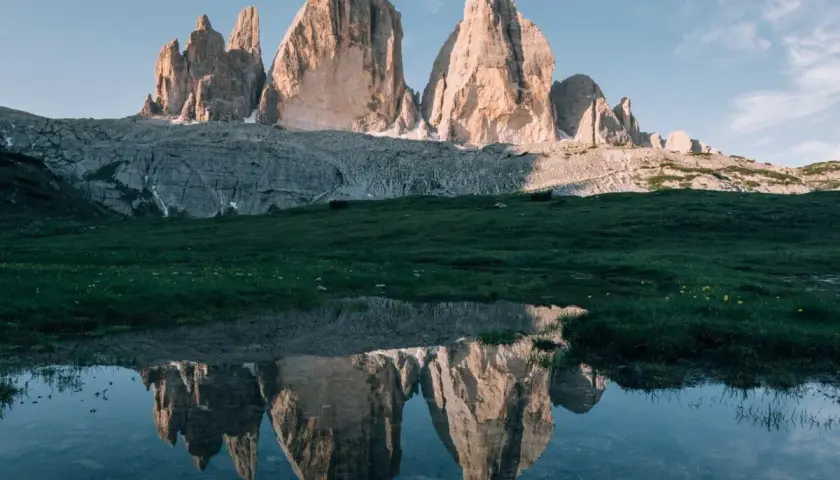 Les Trois Cimes de Lavaredo se reflètent dans un étang près de Misurina, sous un ciel bleu clair.