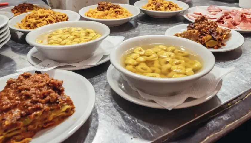 Un festin de pâtes et de charcuterie dans un restaurant de Bologne. Lasagnes, tortellinis en bouillon, tagliatelles à la bolognaise et assiette de jambons.