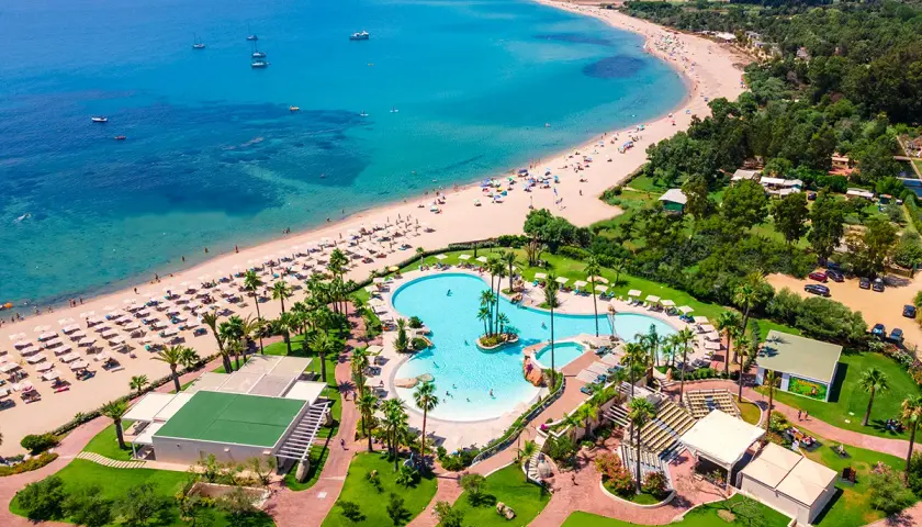 Vue aérienne du **hôtel club Saraceno** avec sa plage de sable fin, sa mer turquoise et sa piscine spectaculaire.