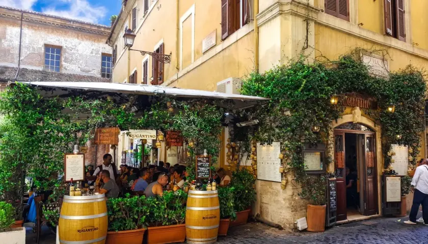 Un charmant restaurant à Rome, "Antica Osteria Rugantino", envahi par la végétation. Idéal pour savoir où manger à Rome.