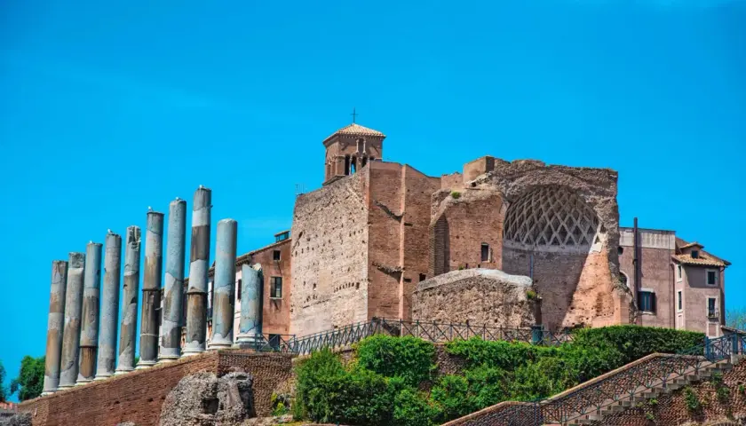 Vestiges de la Domus Aurea, avec ses colonnes antiques et ses ruines de briques sous un ciel bleu éclatant.