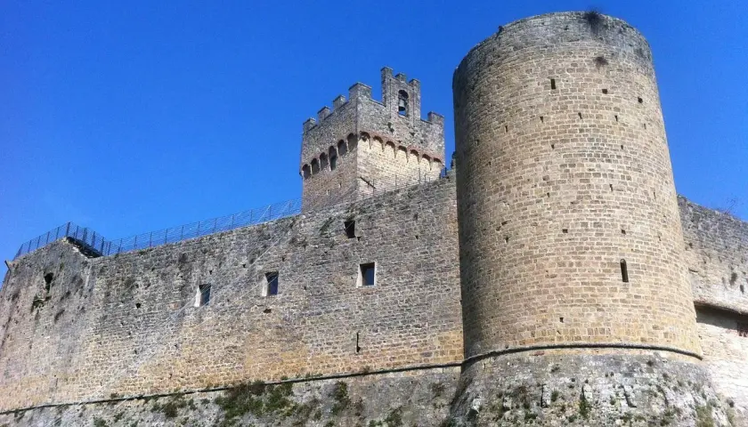 Château médiéval imposant à Poggibonsi, Italie, avec ses tours rondes et carrées sous un ciel bleu éclatant.