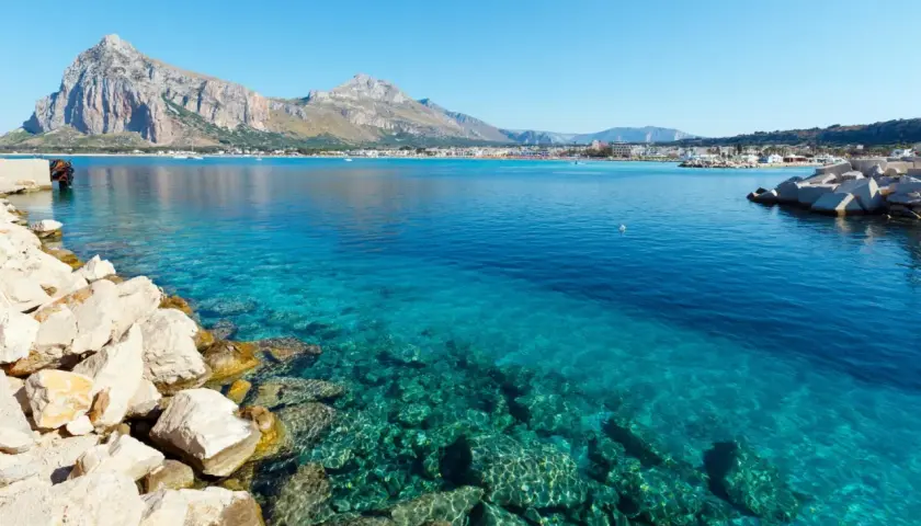 Vue sur la mer turquoise et les montagnes de Capo San Vito. Des rochers blancs bordent la côte.