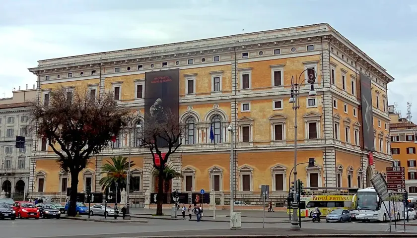 Le **Palazzo Massimo alle Terme**, un édifice majestueux, se dresse fièrement, orné d'une bannière publicitaire.
