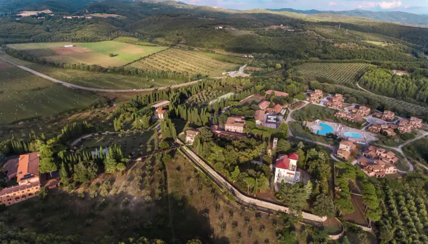 Vue aérienne du Pian dei Mucini, un domaine toscan avec des villas, des cyprès et une piscine.