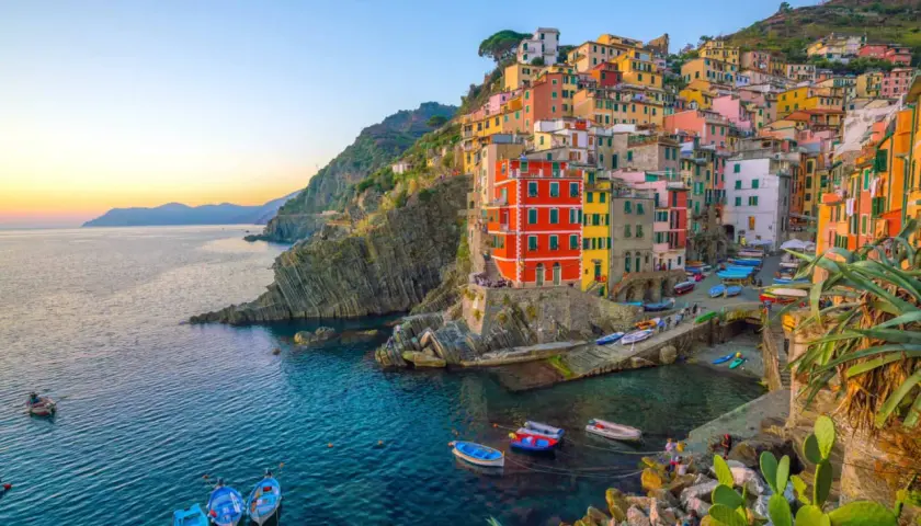 Village vacances La Spezia : maisons colorées accrochées à la falaise, bateaux dans le port, mer bleue.