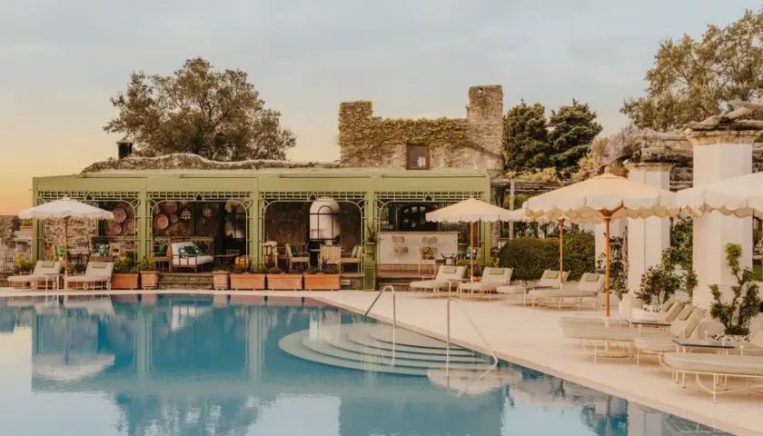 Piscine d'un hôtel club sur la côte amalfitaine, avec des chaises longues, des parasols et un bar extérieur.