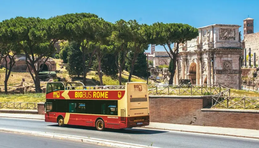 Un bus touristique rouge et jaune circule près de l'Arc de Constantin. Le Vatican n'est pas loin, offrant une vue sur Rome.