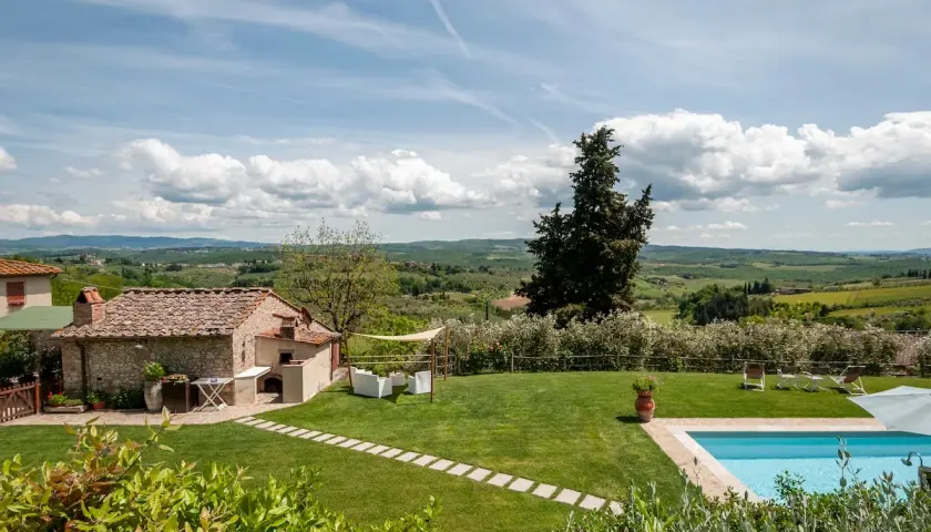 Magnifique vue sur des gîtes en Toscane avec piscine, jardin verdoyant et paysage vallonné sous un ciel bleu.