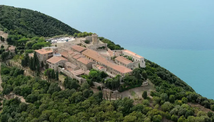 Vue aérienne de Populonia, Italie, un village médiéval perché sur une colline verdoyante surplombant la mer d'un bleu profond.