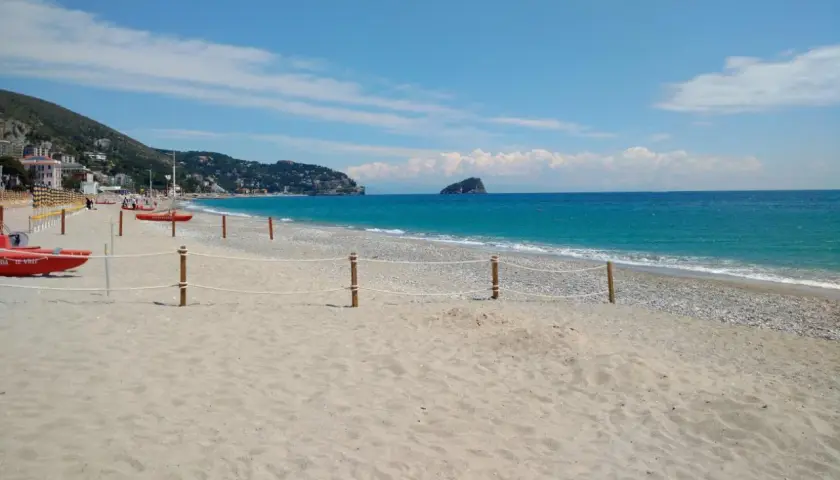 Plage de sable et de galets à Spotorno, Italie. Deux canots de sauvetage rouges sont prêts sur le sable, face à la mer bleue.