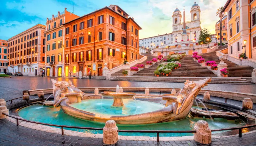 Fontaine de la Barcaccia et l'escalier d'Espagne à Rome au lever du soleil, avec des fleurs colorées.