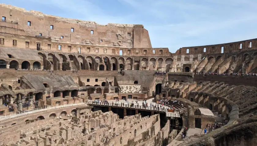 Vue intérieure du Colisée de Rome, vestiges de l'arène et des gradins, avec des touristes explorant ce monument historique.