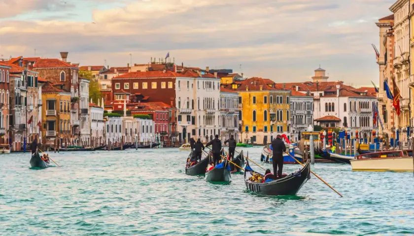 Gondoles glissant sur le Grand Canal, un jour d'octobre à Venise. Les façades colorées des palais se reflètent dans l'eau calme.