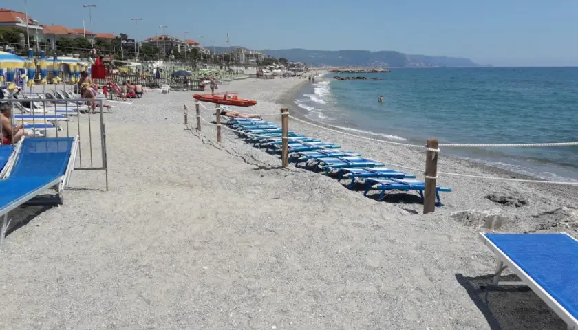 Plage de Loano, Italie, avec des chaises longues bleues alignées près de la mer Méditerranée.
