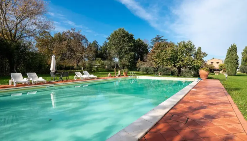 Piscine d'un gîte en Italie, entourée de verdure et de transats. Idéal pour des vacances paisibles.