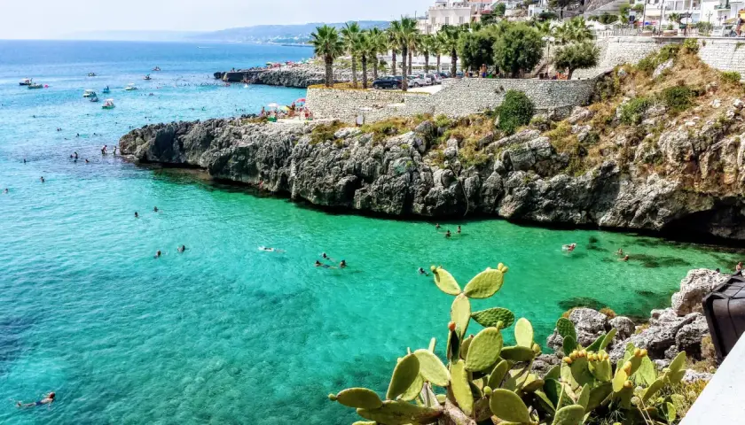 Plage rocheuse et eaux turquoise à Castro, Italie. Des baigneurs profitent du soleil et de la mer.