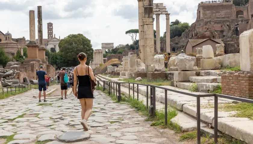 Une femme se promène sur une voie pavée dans le Forum romain, un site idéal pour visiter Rome en 4 jours.