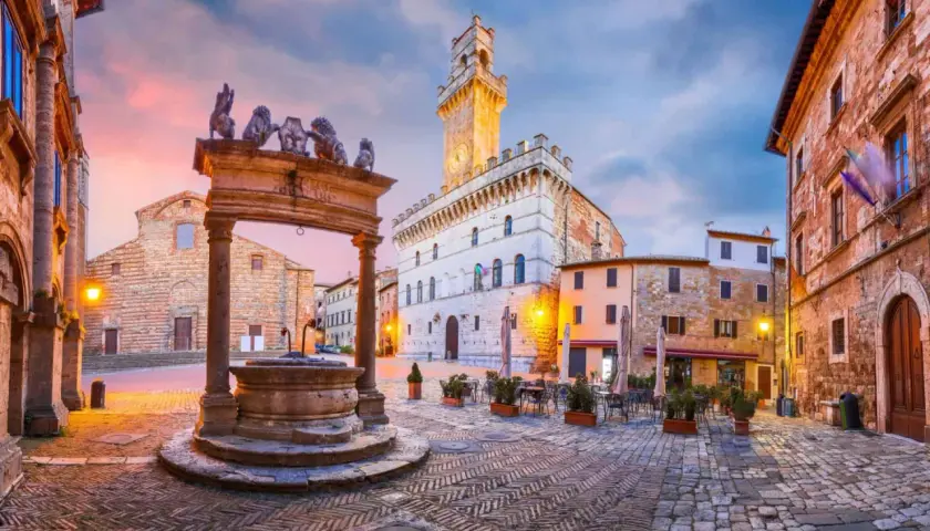 Place du peuple à Montepulciano, Toscane, avec sa fontaine ornée de lions et son hôtel de ville imposant.