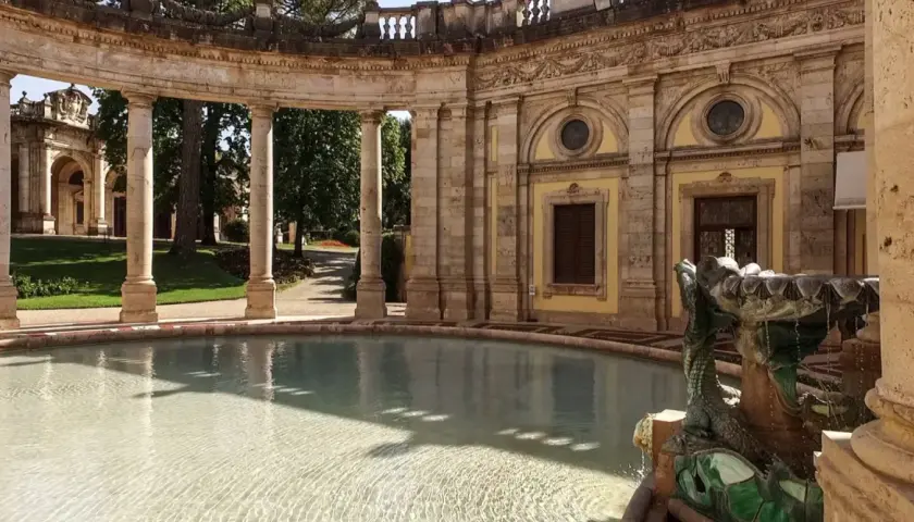 Fontaine sculptée d'un dragon à Montecatini, avec une arcade de colonnes en arrière-plan et un bassin d'eau claire.