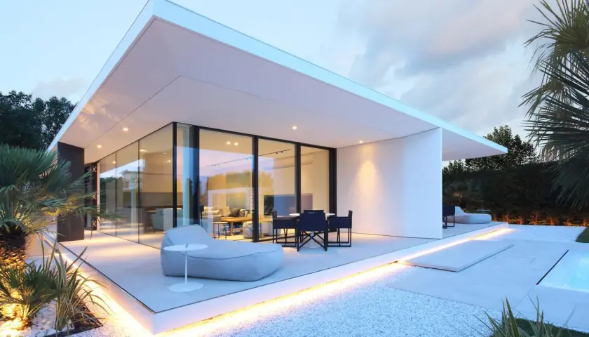 Villa moderne à Jesolo avec grandes baies vitrées, terrasse illuminée et mobilier extérieur invitant.