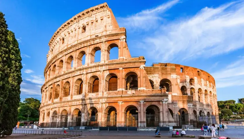 Le Colisée de Rome en novembre, sous un ciel bleu éclatant. Des visiteurs profitent de la douceur de l'automne.