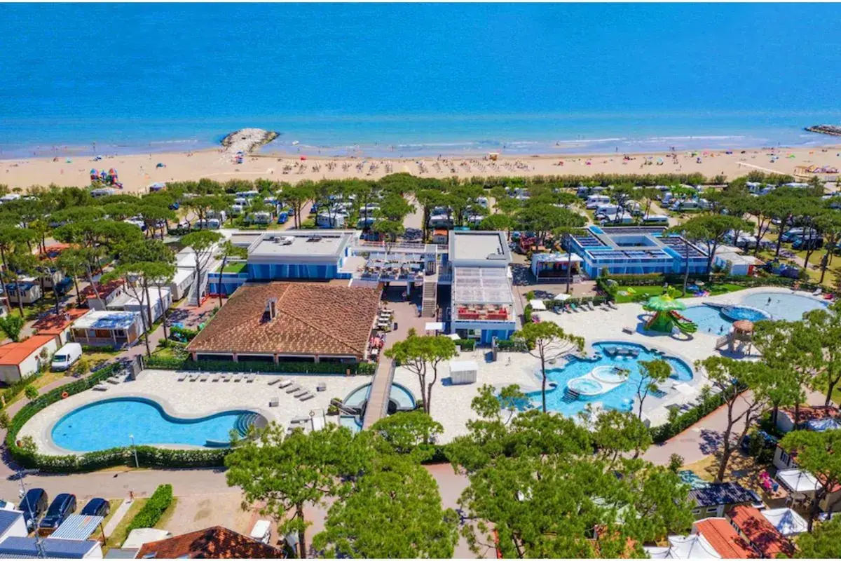 Vue aérienne d'un camping et d'une plage à Cavallino, Italie. Piscines, mobil-homes et mer bleue.