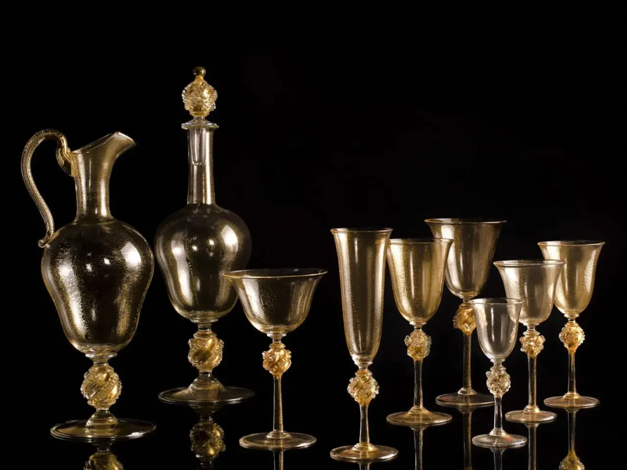 Service en verre doré, digne d'un musée du verre à Venise, avec carafe et verres aux pieds sculptés.