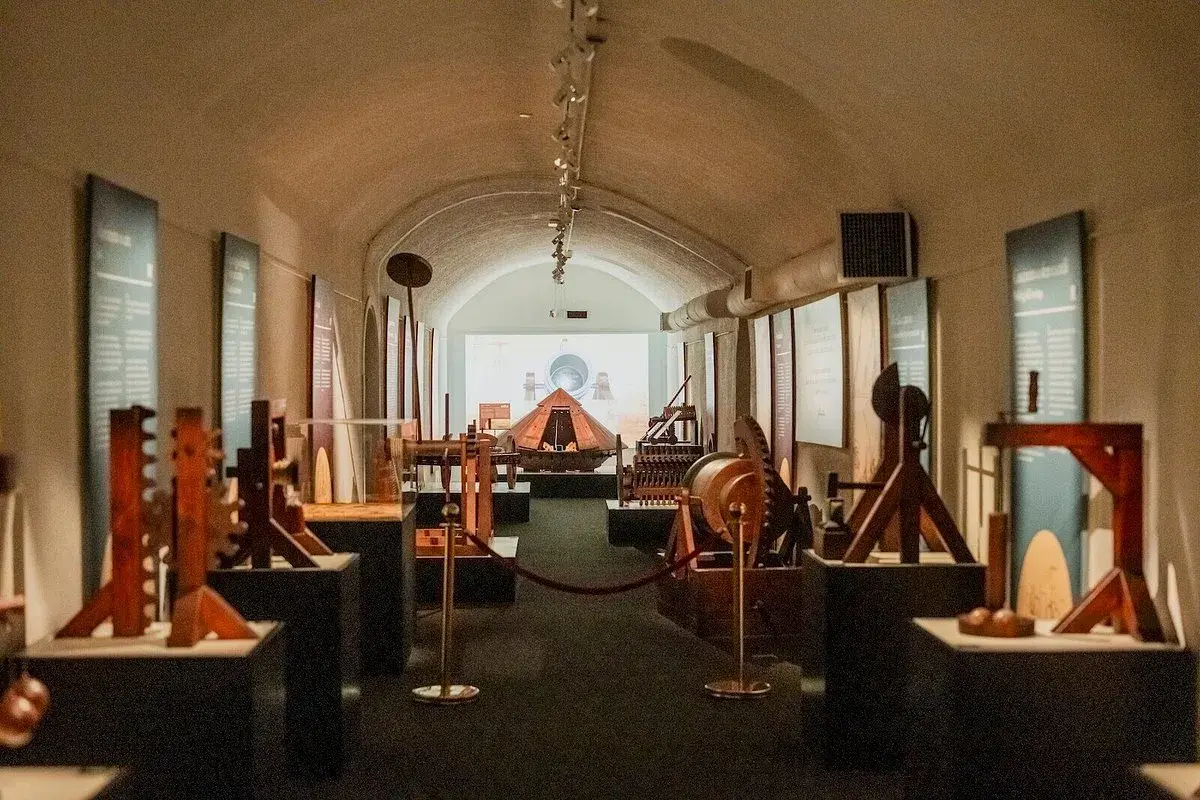 Maquettes d'inventions de Léonard de Vinci exposées dans un couloir voûté, une invitation à explorer le musée Léonard de Vinci à Rome.