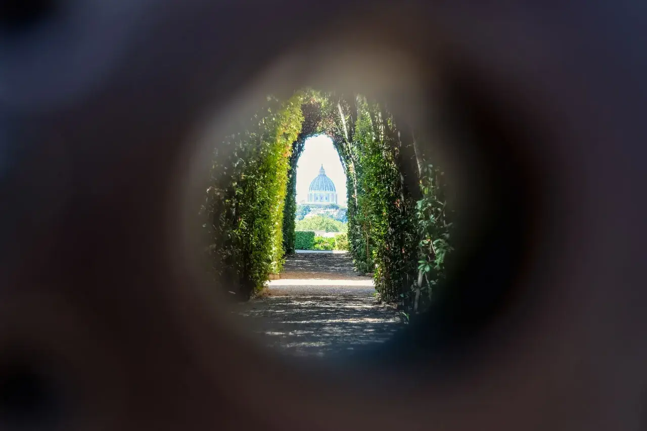 Un chemin bordé de verdure mène à la coupole de Saint-Pierre, une vision de Rome insolite et secrète à travers un trou de serrure.