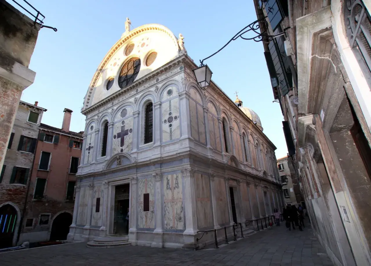 La façade en marbre de Santa Maria dei Miracoli à Venise, ornée d'une grande rosace et d'une croix.