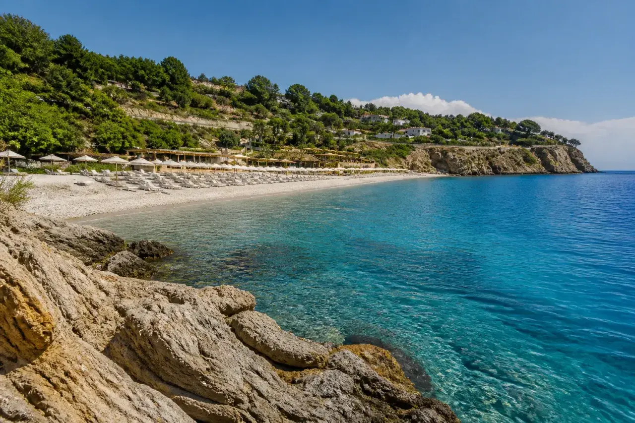 Plage de galets et eaux turquoises à Alassio, Italie. Des rangées de parasols et de chaises longues invitent à la détente sous le soleil.