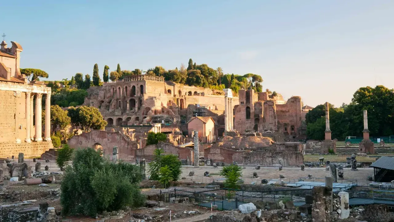 Ruines antiques sur le mont Palatin à Rome, baignées par la lumière dorée du soleil. Des colonnes brisées et des murs de briques témoignent de la grandeur passée.