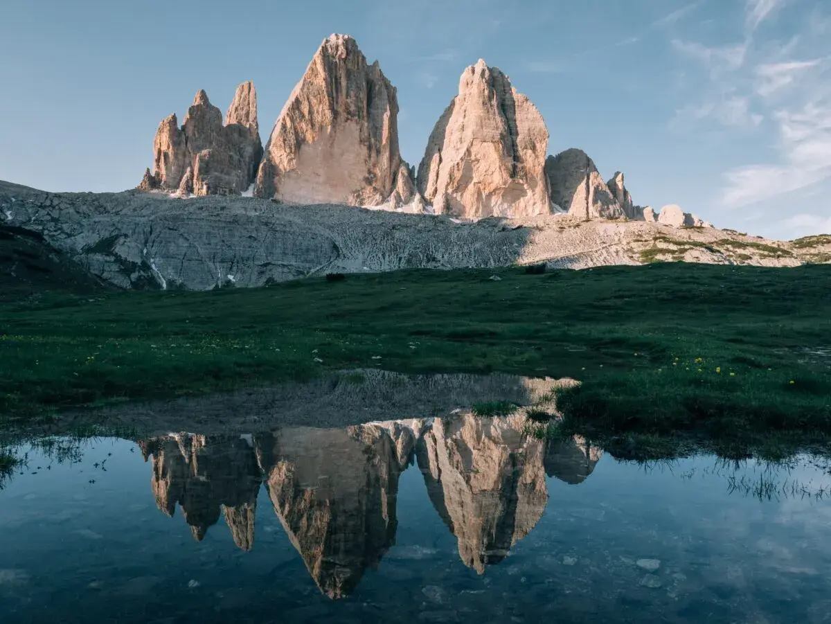 Les Trois Cimes de Lavaredo se reflètent dans un étang près de Misurina, sous un ciel bleu clair.
