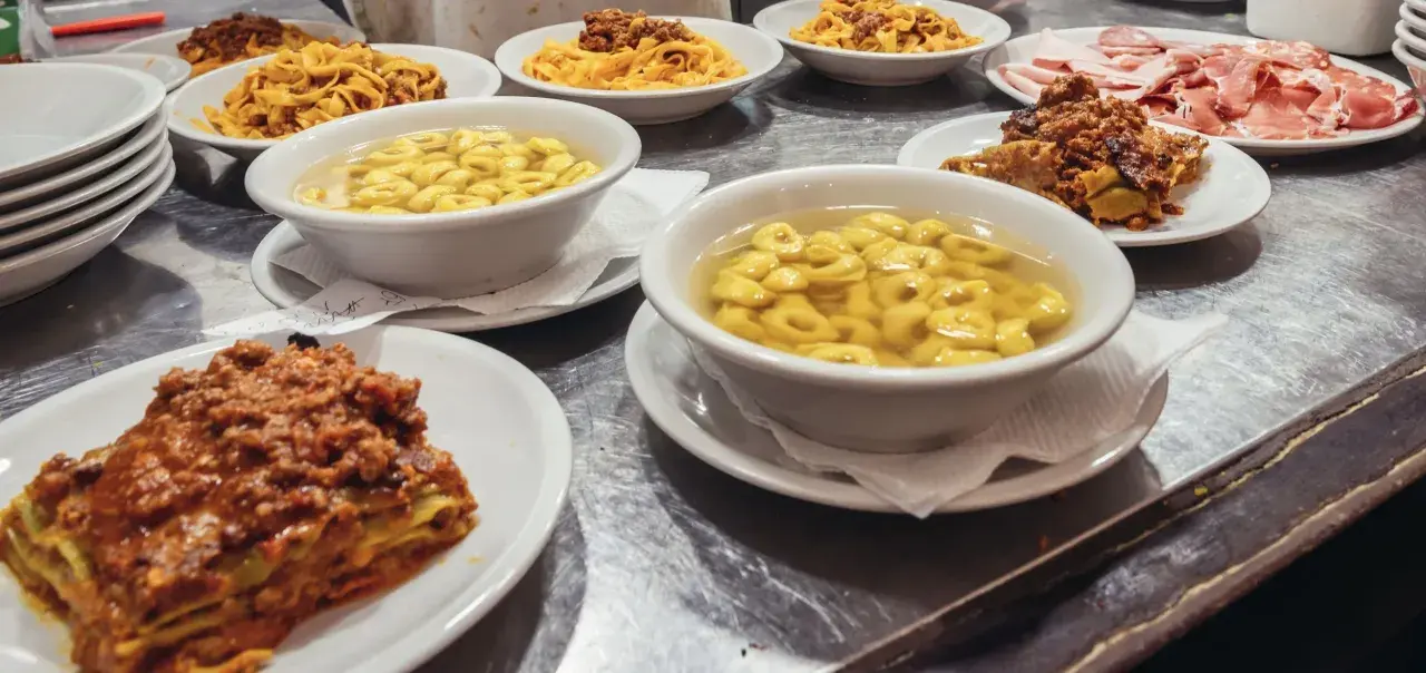Un festin de pâtes et de charcuterie dans un restaurant de Bologne. Lasagnes, tortellinis en bouillon, tagliatelles à la bolognaise et assiette de jambons.