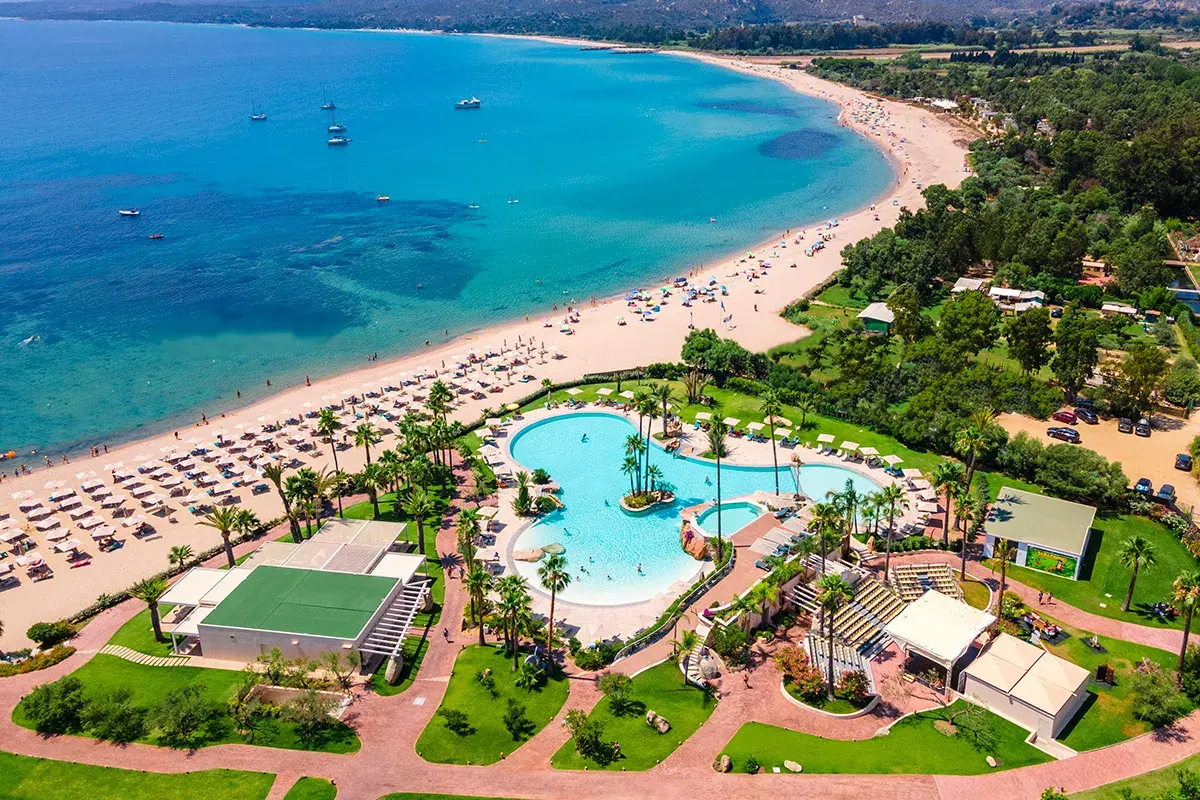 Vue aérienne du **hôtel club Saraceno** avec sa plage de sable fin, sa mer turquoise et sa piscine spectaculaire.