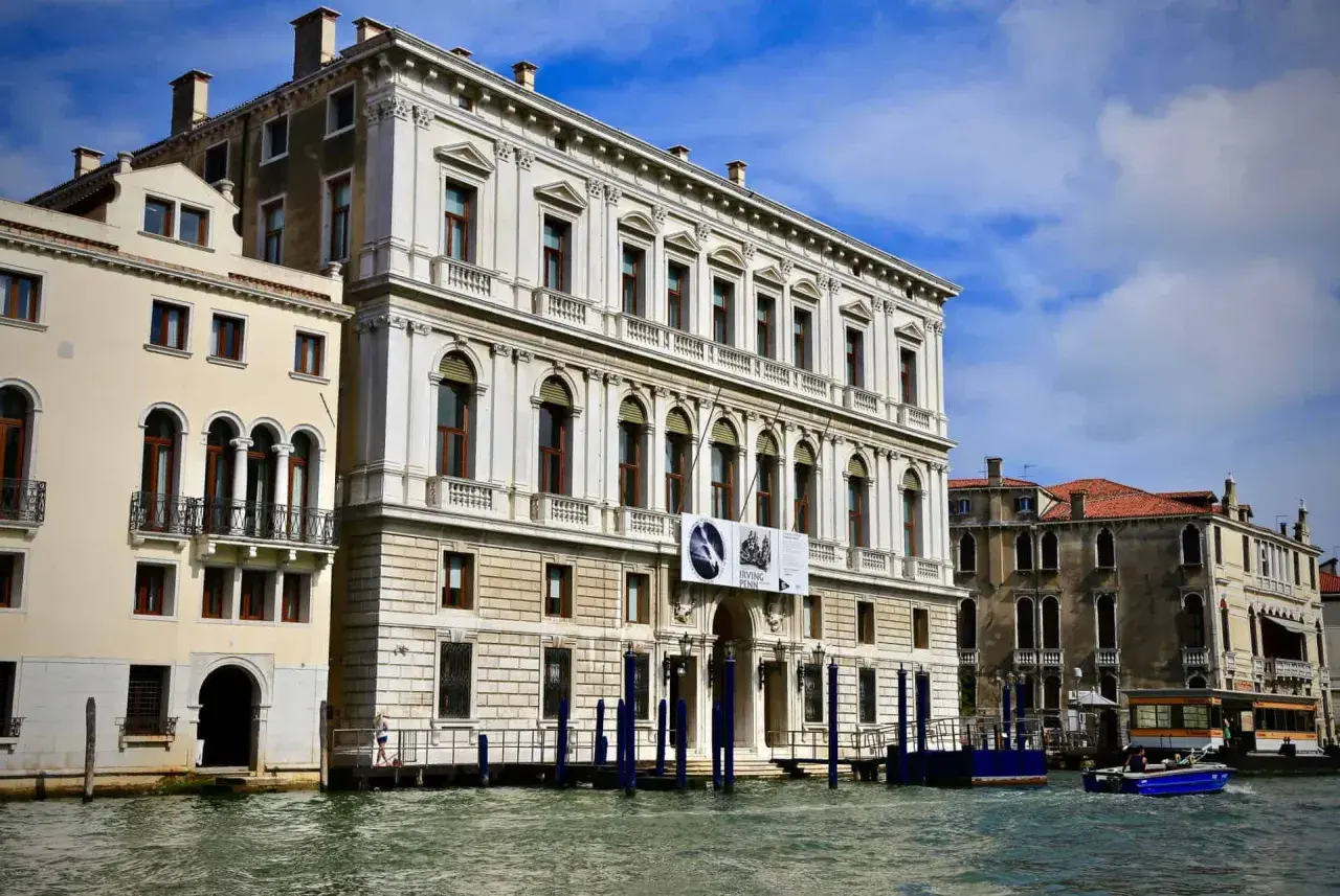 Le **Palazzo Grassi** à Venise, majestueux édifice blanc, se reflète dans le Grand Canal. Une exposition Irving Penn y est annoncée.