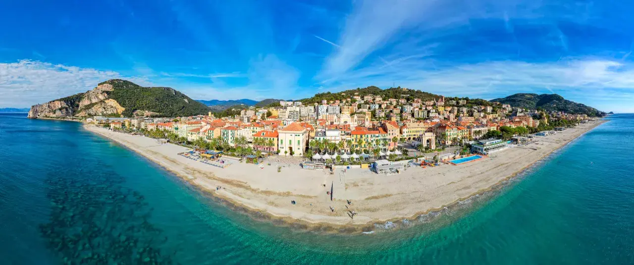 Vue panoramique de la plage et de la ville colorée de Finale Ligure, Italie, sous un ciel bleu éclatant.